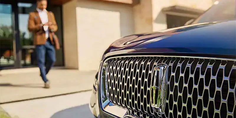 A man walking up to his Lincoln vehicle.