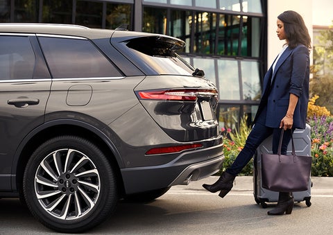 A woman with her hands full uses her foot to activate the available hands-free liftgate. | Korum Lincoln in Puyallup WA