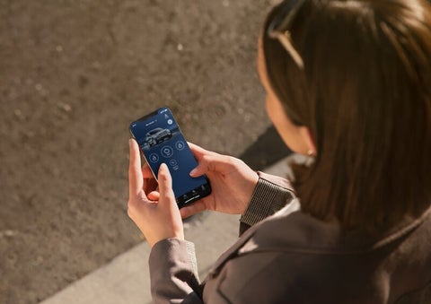A person is shown interacting with a smartphone to connect to a Lincoln vehicle via the Lincoln Way® App. | Korum Lincoln in Puyallup WA