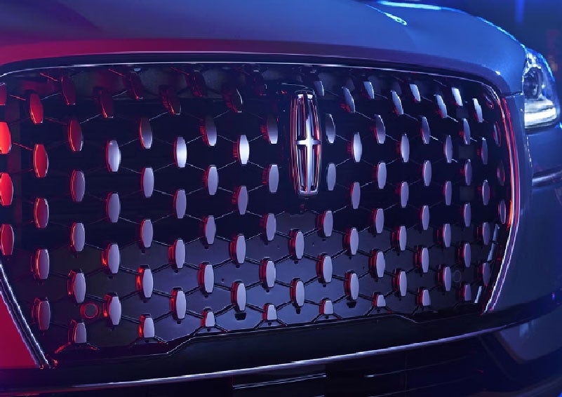 The grille of a 2025 Lincoln Corsair® SUV reflects neon light at night. | Korum Lincoln in Puyallup WA