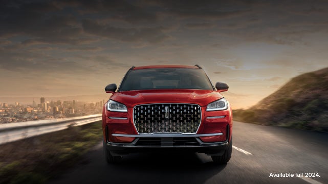 A 2025 red Lincoln Corsair® SUV is being driven down a road at sunset. | Korum Lincoln in Puyallup WA