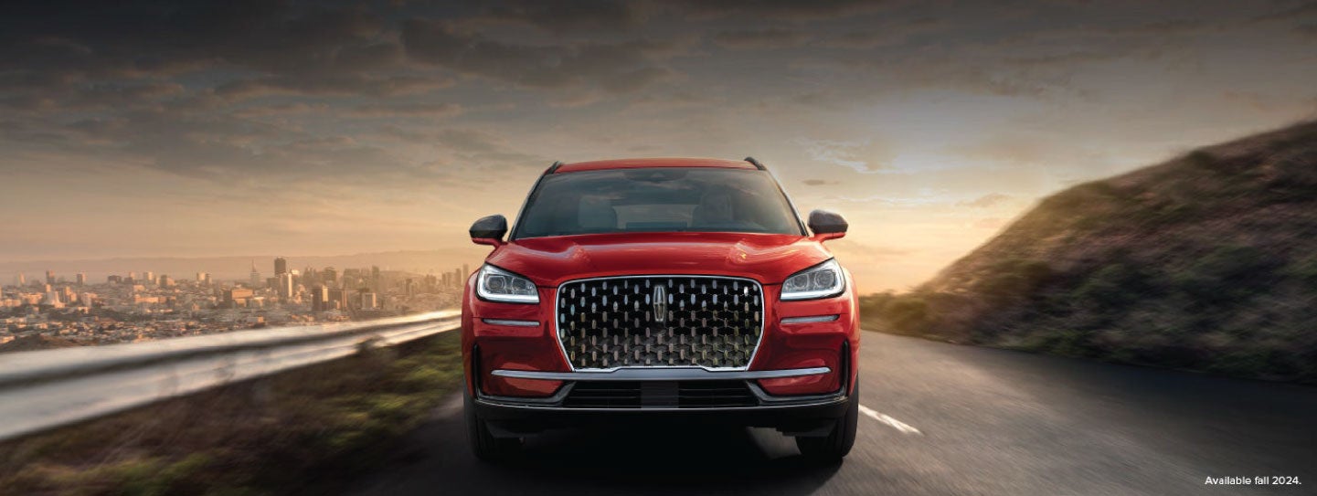 A 2025 red Lincoln Corsair® SUV is being driven down a road at sunset. | Korum Lincoln in Puyallup WA