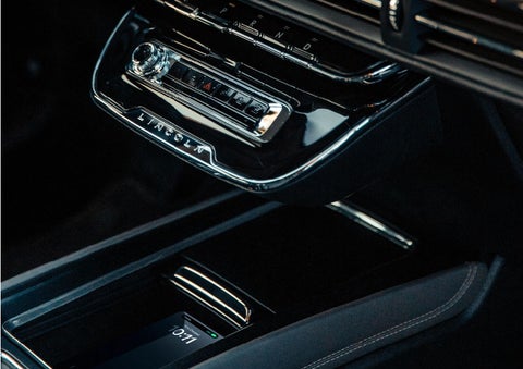A smartphone is is being placed on the wireless charging pad in the front center console cubby. | Korum Lincoln in Puyallup WA