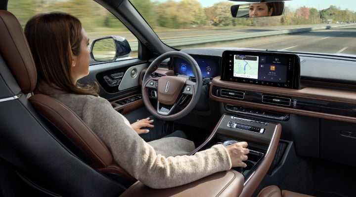 A 2026 Lincoln Aviator® SUV is being driven hands-free on a highway near a forest | Korum Lincoln in Puyallup WA