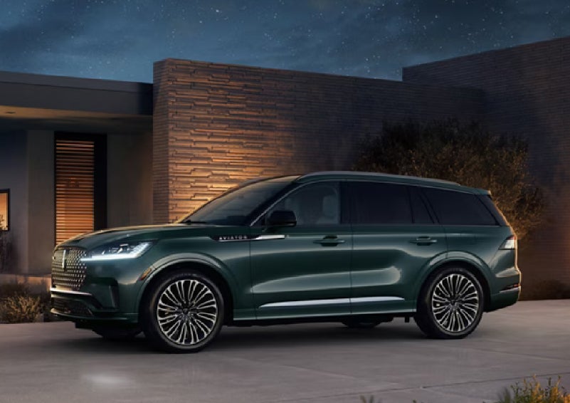 A green 2027 Lincoln Aviator® SUV is parked outside a contemporary home. | Korum Lincoln in Puyallup WA