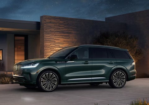 A green 2027 Lincoln Aviator® SUV is parked outside a contemporary home. | Korum Lincoln in Puyallup WA