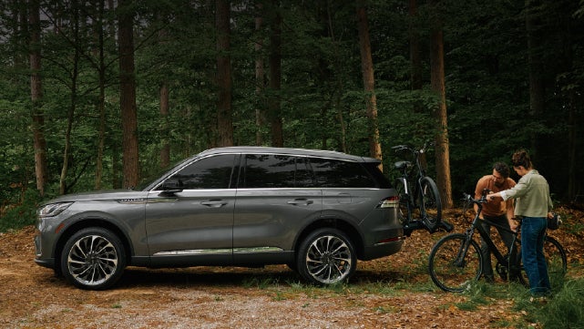 A father and son load e-bikes on a bike rack attached to a 2027 Lincoln Aviator® SUV. | Korum Lincoln in Puyallup WA
