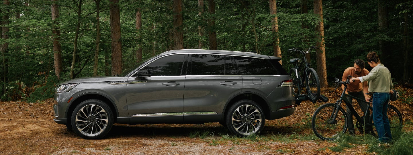 A father and son load e-bikes on a bike rack attached to a 2027 Lincoln Aviator® SUV. | Korum Lincoln in Puyallup WA
